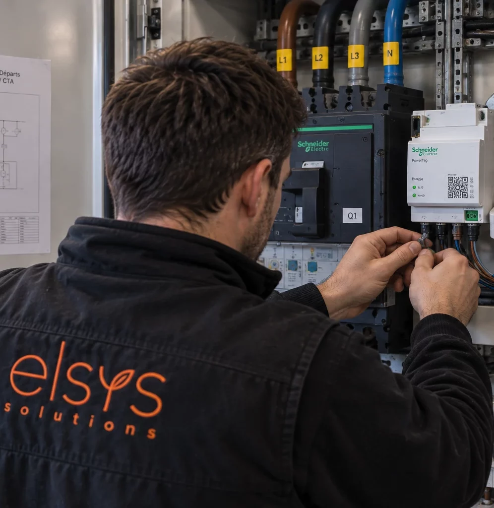 Technicien ELSYS raccordant un module de mesure et de communication dans une armoire électrique.
